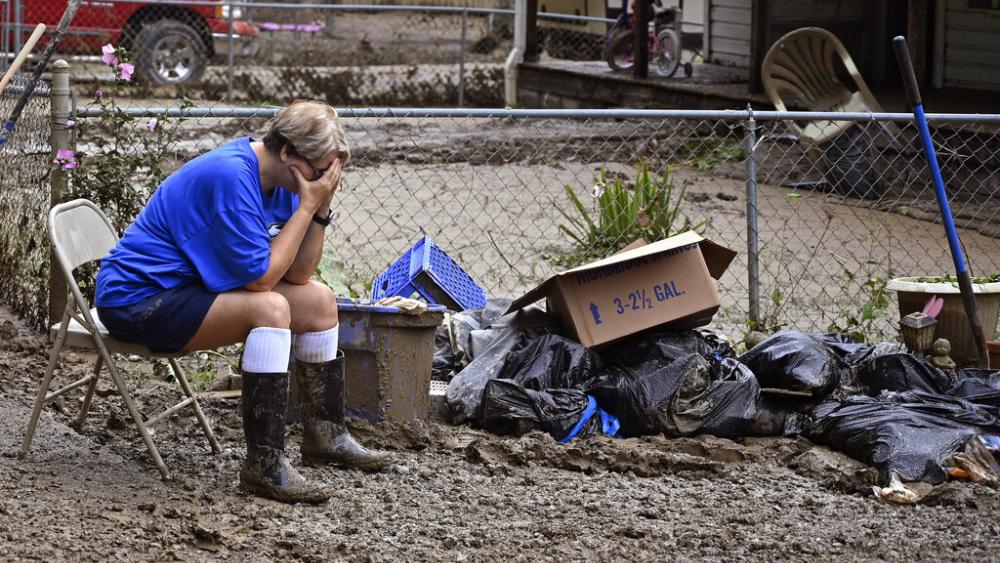 Teresa Reynolds sits exhausted as members of her community clean the debris from their flood ravaged homes in Ogden Hollar at Hindman, Ky., Saturday, July 30, 2022. (AP Photo/Timothy D. Easley)