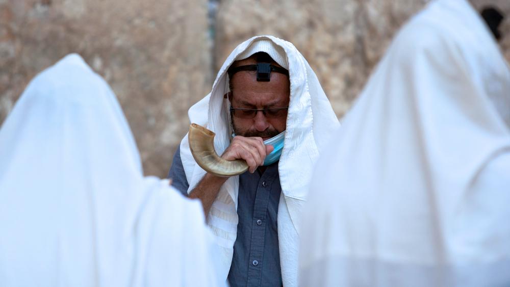 An ultra-Orthodox Jewish man blows a shofar, a musical instrument made from an animal horn, as he prays ahead of the Jewish new year at the Western Wall.(AP Photo/Sebastian Scheiner)
