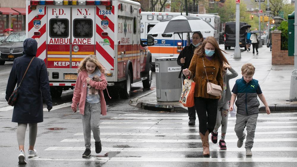 A family walks by ambulances parked outside NewYork–Presbyterian Brooklyn Methodist Hospital, May 6, 2020 in New York during the coronavirus pandemic. (AP Photo/Mark Lennihan)