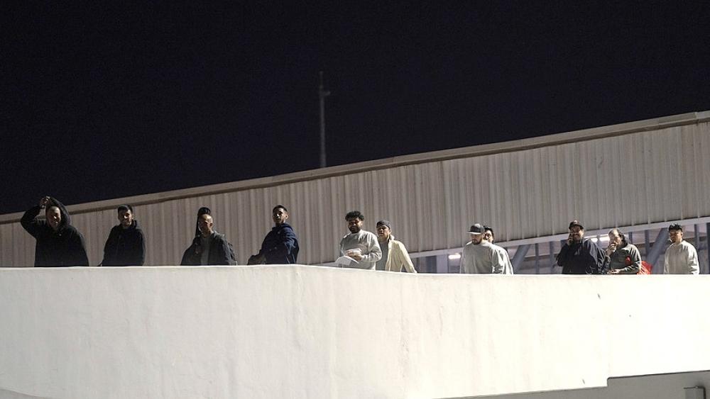 Migrants walk back into Mexico after being deported from the U.S., at El Chaparral pedestrian border bridge in Tijuana, Mexico, late Tuesday, Jan. 21, 2025. (AP Photo/Felix Marquez)