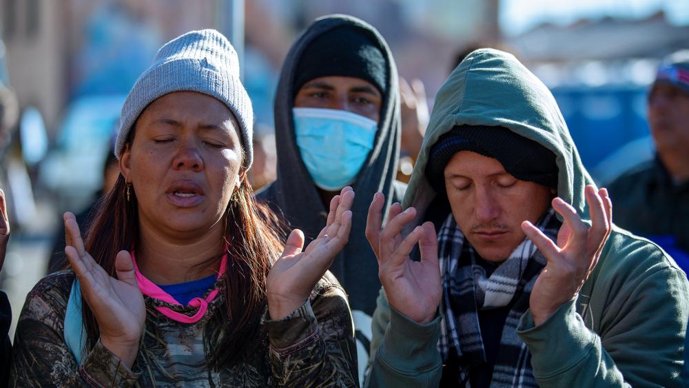 Venezuelan migrants pray at the camping site outside the Sacred Heart Church in downtown El Paso, Texas, Sunday, Jan. 8, 2023. (AP Photo/Andres Leighton) 