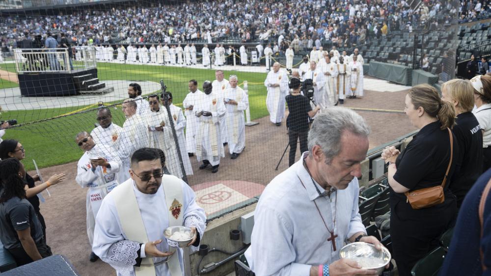 Priests bring Communion to attendees during the Archdiocese of Chicago&#039;s celebration of Pope Leo XIV at Rate Field, Saturday, June 14, 2025. (Pat Nabong/Chicago Sun-Times via AP)