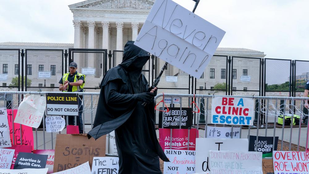 A man dressed as the grim reaper stands amid pro-abortion signs at the Supreme Court, May 14, 2022. (AP Photo/Jacquelyn Martin)