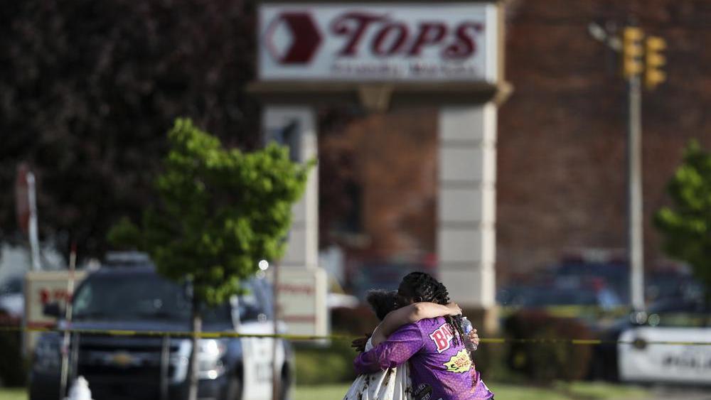 People hug outside the scene after a shooting at a supermarket on Saturday, May 14, 2022, in Buffalo, N.Y. (AP Photo/Joshua Bessex)