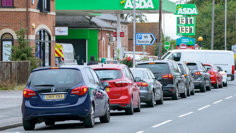 Cars queue outside a petrol station in Reading, England. Motorists have formed long lines as they try to fill up in case of further disruption. (Steve Parsons/PA via AP)