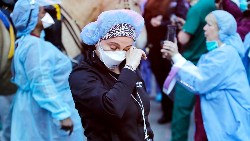 A medical worker reacts as police officers and pedestrians cheer medical workers outside NYU Medical Center, April 16, 2020, in New York. (AP Photo/Frank Franklin II)