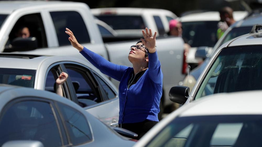 A church goer stands by her car as she worships in the parking lot in San Antonio, April 12, 2020. (AP Photo/Eric Gay) 