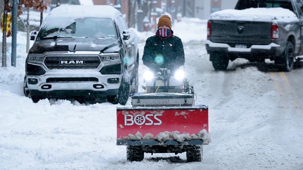 A worker drives a sidewalk snow plow down the middle of a street on Pittsburgh&#039;s Northside on Monday, Jan. 17, 2022. (AP Photo/Gene J. Puskar)