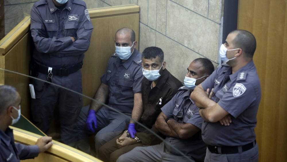 Mohammed Aradeh, center, is surrounded by guards in a courtroom in Nazareth, Israel, after he and three other Palestinian fugitives were captured on Saturday, Sept. 11, 2021. (AP Photo/Sebastian Scheiner)