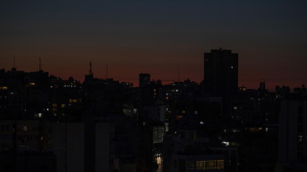 n this Monday, March 29, 2021 file photo, the capital city of Beirut remains in darkness during a power outage as the sun sets, in Lebanon.  (AP Photo/Hassan Ammar, File)
