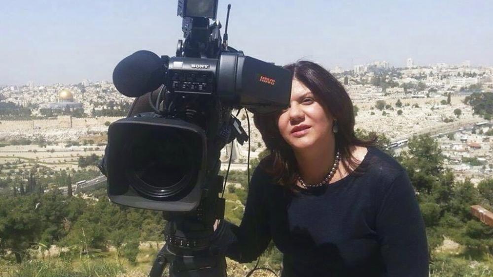 In this undated photo provided by Al Jazeera Media Network, Shireen Abu Akleh, a journalist for Al Jazeera network, stands next to a TV camera. (Al Jazeera Media Network via AP)