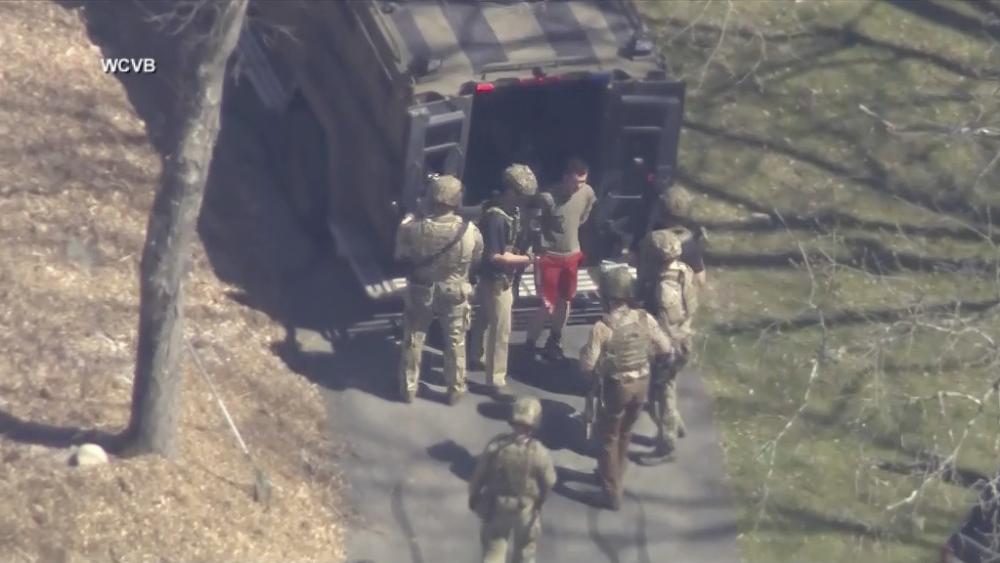 This image made from video provided by WCVB-TV, shows Jack Teixeira, in T-shirt and shorts, being taken into custody by armed tactical agents on Thursday, April 13, 2023, in Dighton, Mass. (WCVB-TV via AP)