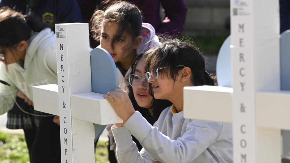 Children sign a cross at an entry to Covenant School, Tuesday, March 28, 2023, in Nashville, Tenn., which has become a memorial to the victims of Monday&#039;s school shooting. (AP Photo/John Amis)