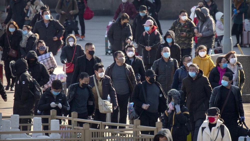 Travelers wear face masks as they walk outside the Beijing Railway Station in Beijing, Saturday, Feb. 15, 2020. 