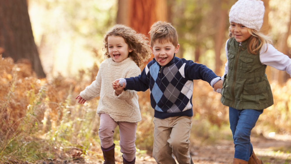 happy children holding hands on a nature path in autumn
