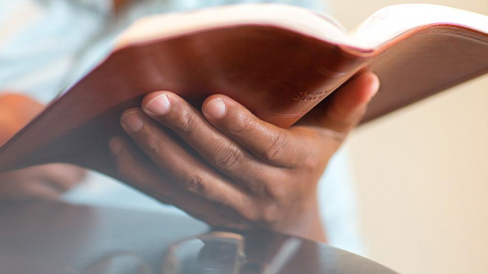 close up of an open Bible in a man&#039;s hand