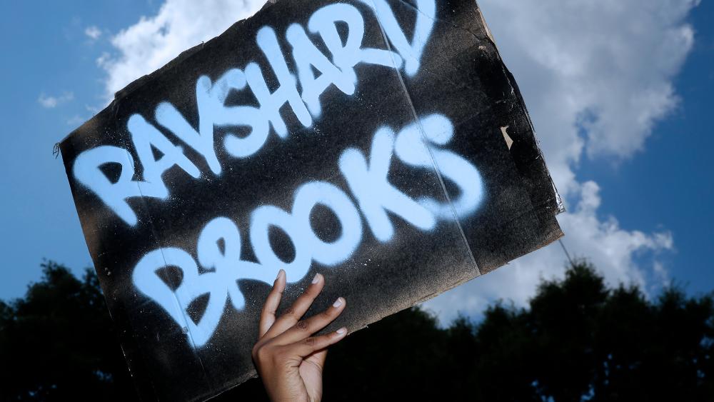 A protester holds up a sign near the Wendy&#039;s restaurant where Rayshard Brooks was shot and killed by police Friday evening following a struggle in the restaurant&#039;s drive-thru line in Atlanta. (AP Photo/Brynn Anderson)