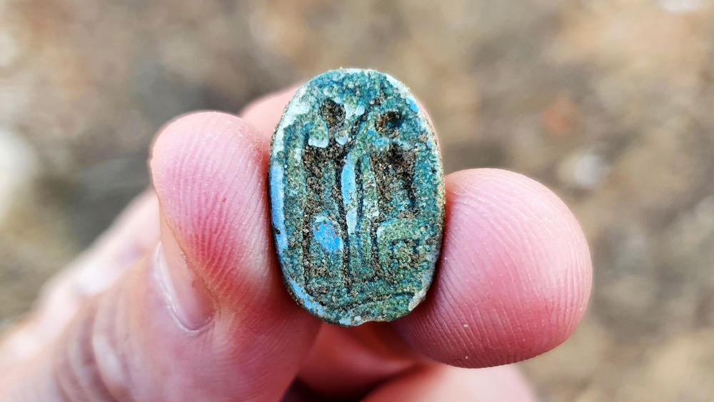 The scarab, showing a seated figure on the right and a standing figure with a raised arm on the left, possibly symbolizing the imparting of authority. Photo: Gilad Stern, Israel Antiquities Authority.